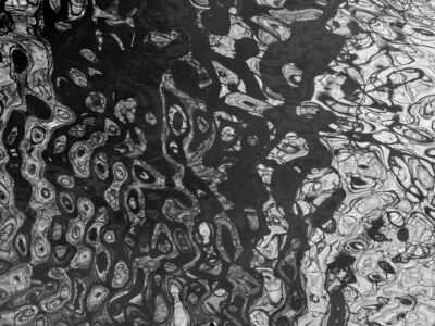 Black and white abstract water texture with rippled reflections and organic circular shapes, high-contrast photograph