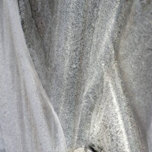 Close-up abstract texture of silver-grey ice and frost layers with flowing striations and crystalline granularity
