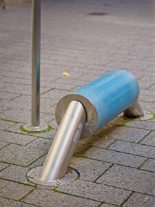 Stainless steel public bench with cylindrical blue padded seat on grey city paving, Delmenhorst street furniture photograph